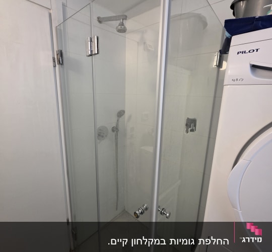 מקלחון זכוכית פינתי מותקן בחדר רחצה עם דלתות ציר